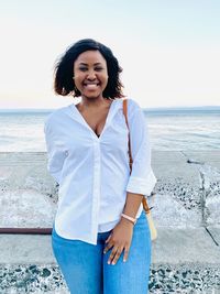 Happy woman standing at beach against sky