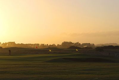 Distant person playing golf at sunset