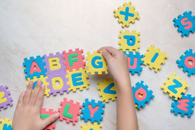 Cropped hand of child playing with alphabets on puzzles at floor