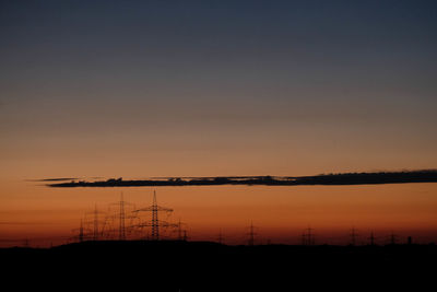 Silhouette electricity pylon against sky during sunset