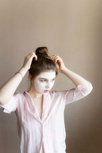 Portrait of young woman standing against wall