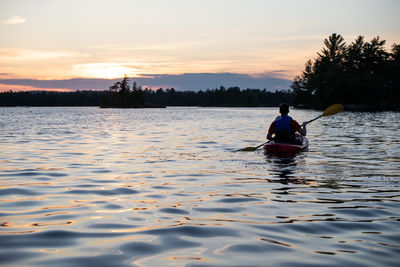 Rear view of boy kayaking in lake