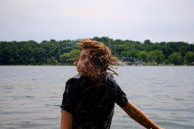 Boy tossing hair in lake