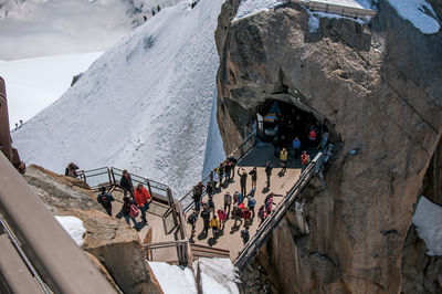 Footbridge between rocky peaks with tourists on the aiguille du midi, near chamonix, france.