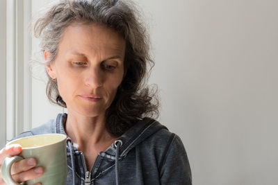 Thoughtful woman holding coffee cup at home