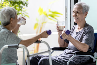 Senior women drinking milk while holding dumbbells