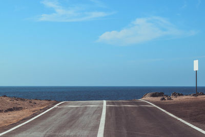 Empty road by sea against sky