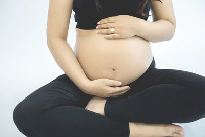 Midsection of woman sitting against white background