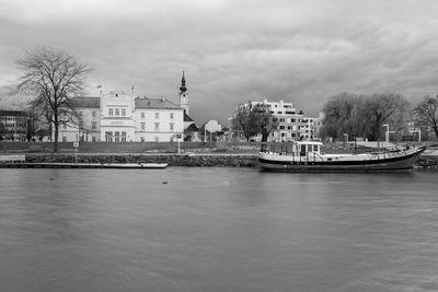 Buildings by river against sky in city