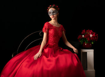 Midsection of woman with red flower against black background