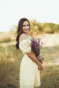 Portrait of smiling young woman standing on field