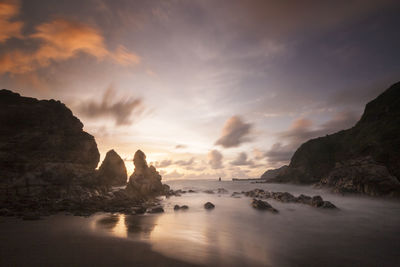 Rocks on sea against sky during sunset