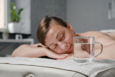 Beautiful young woman with cup of water relaxing in spa salon. woman in spa in sauna resting. hot