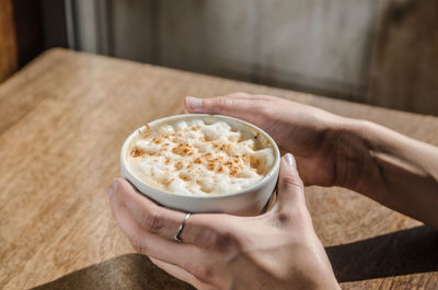Cropped image of hands holding latte macchiato on table