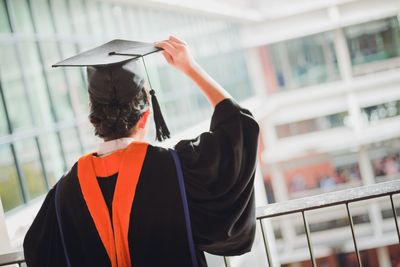 Rear view of woman wearing graduation gown and mortarboard