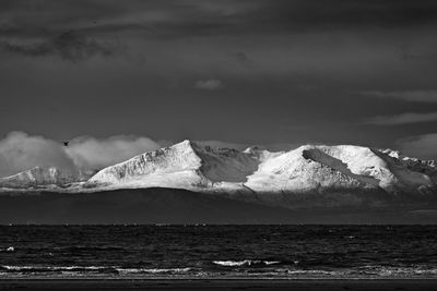 Scenic view of sea and snowcapped mountains against sky