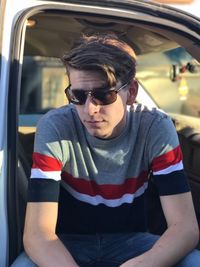 Young man wearing sunglasses sitting in car