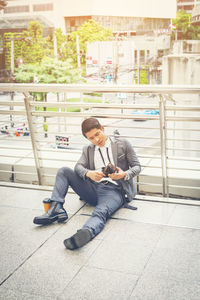 High angle view of businessman looking at wallet while sitting on elevated walkway