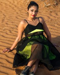 Portrait of woman sitting on sand in desert