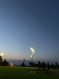 Illuminated street light on field against sky at night