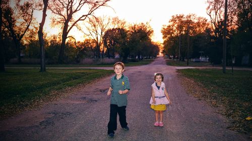Full length portrait of boy and girl standing on road