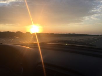 Road by landscape against sky during sunset