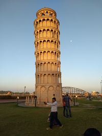 People in front of historical building against clear sky