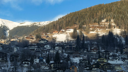 Sunny forest and village houses on winter slopes of austria alps