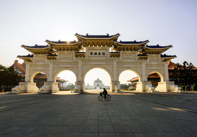 Woman riding bicycle in front of building