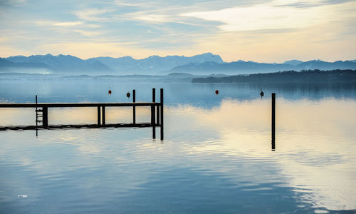 Wooden posts in lake against sky