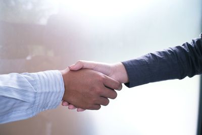 Cropped image of people handshaking by glass