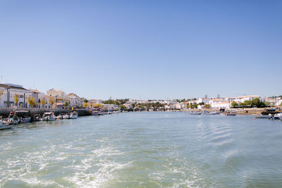 Buildings by sea against clear sky