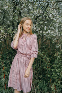 Blonde girl on a spring walk in the garden with cherry blossoms. female portrait, close-up. 
