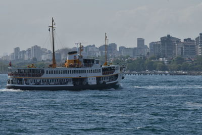 Ship sailing on sea against buildings in city