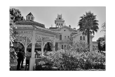 People by palm trees and buildings against sky