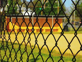 Close-up of chainlink fence by grassy field