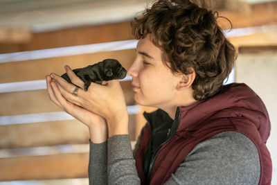 Young man holding puppy sitting at home