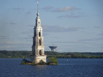 Clock tower by sea against sky