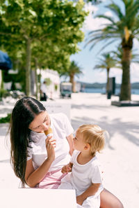 Mother and girl and daughter on tree against trees