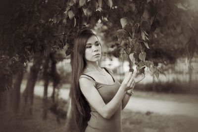 Portrait of young woman standing against tree