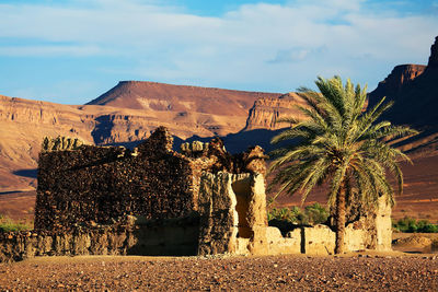 Built structure by atlas mountains at erg chebbi against sky