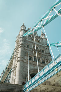 Low angle view of crane by building against sky