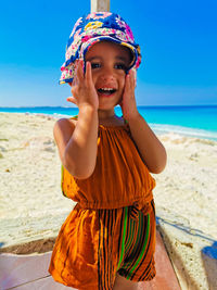 Happy girl standing on beach against sky