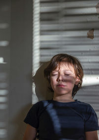 Portrait of boy standing against wall