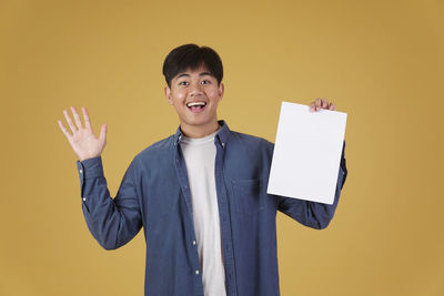 Portrait of a smiling young man against yellow background