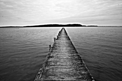 Wooden pier over sea against sky