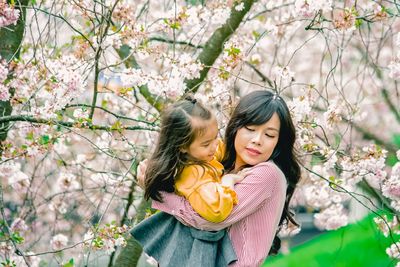 Portrait of a beautiful young woman sitting by cherry tree