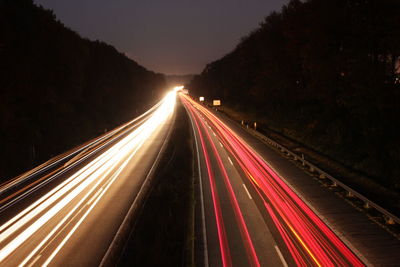 Light trails on road against sky at night