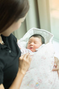 Woman holding newborn baby at home