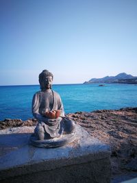 Statue by sea against clear sky